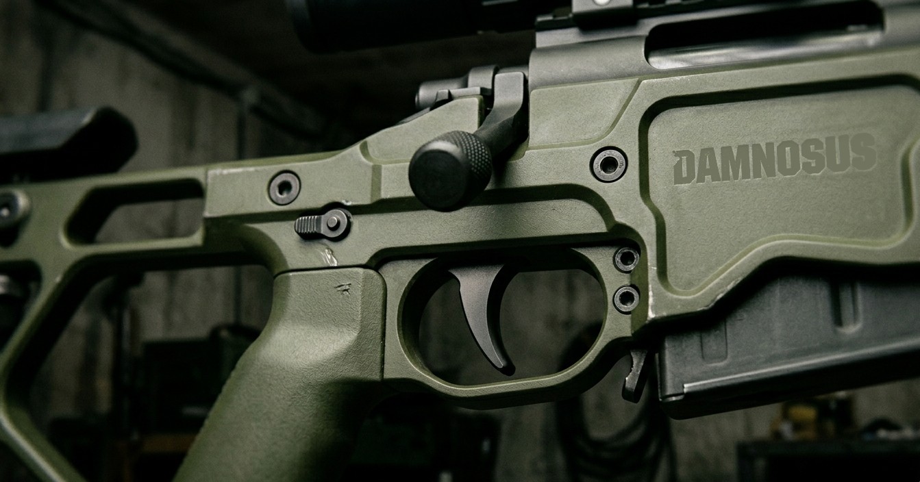 close-up of a precision rifle trigger and action on an OD green Damnosus chassis